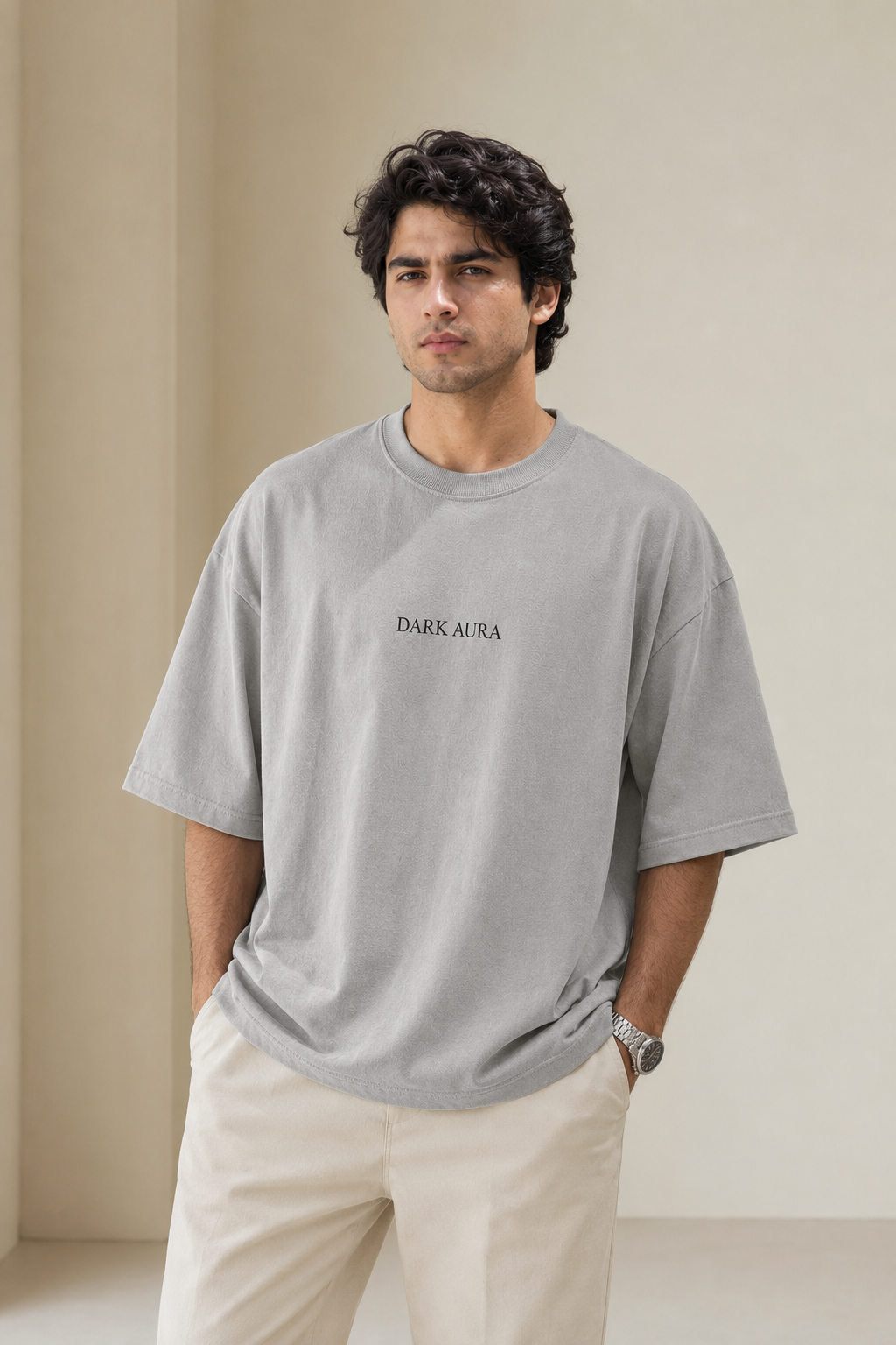 Man wearing a gray t-shirt with 'DARK AURA' text against a beige background