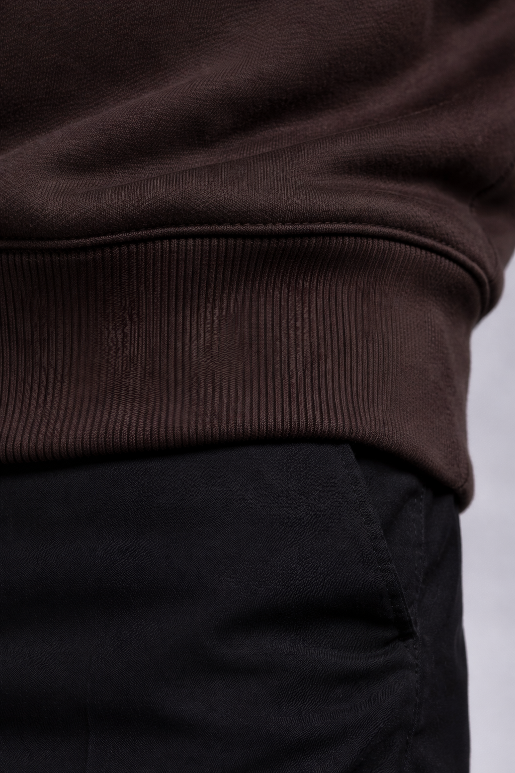 Close-up of a brown sweater and black pants on a white background