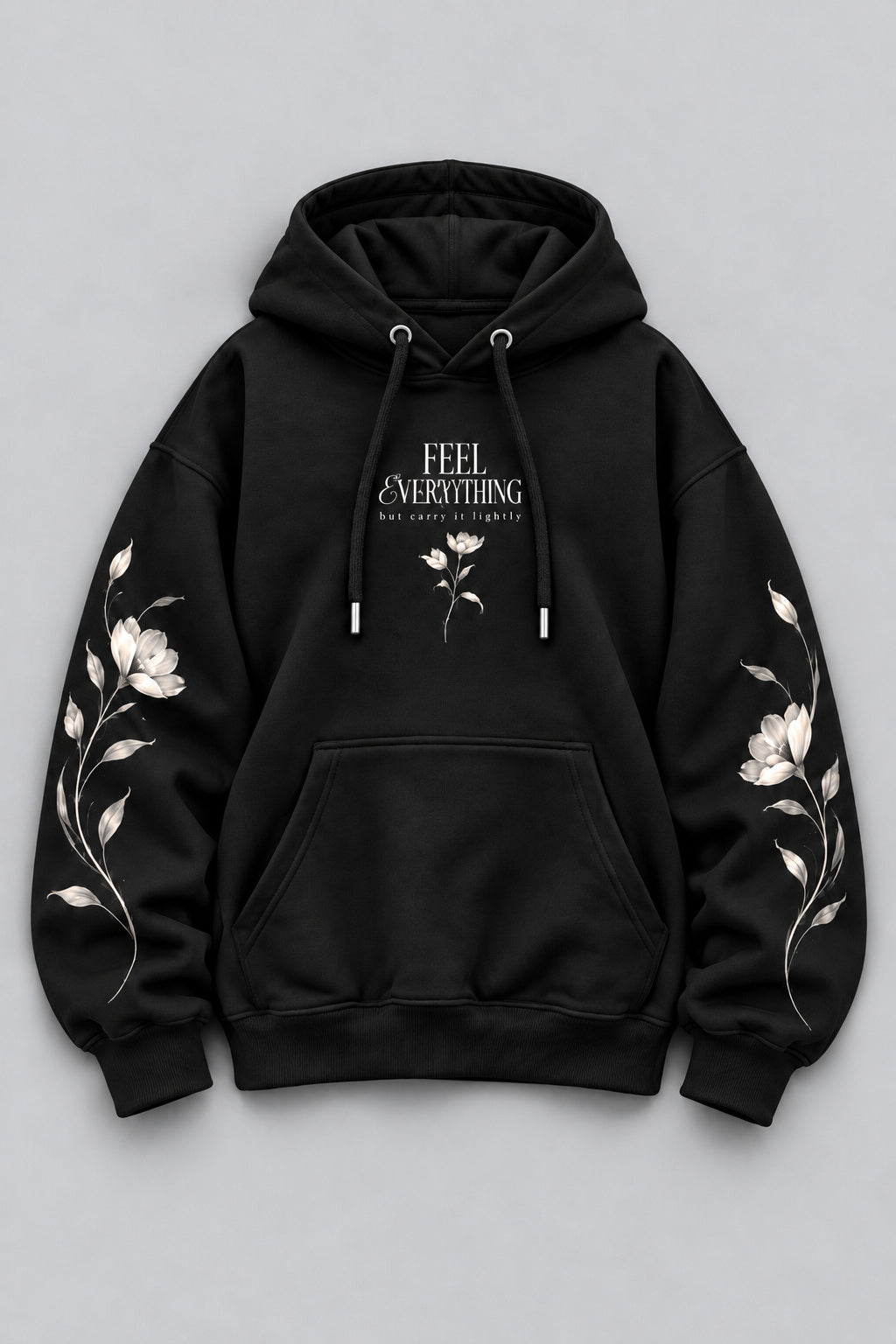 A black pullover hoodie with white floral embroidery on both sleeves and a white graphic print on the chest reading 'FEEL EVERYTHING' with smaller text below, displayed on a neutral gray background.