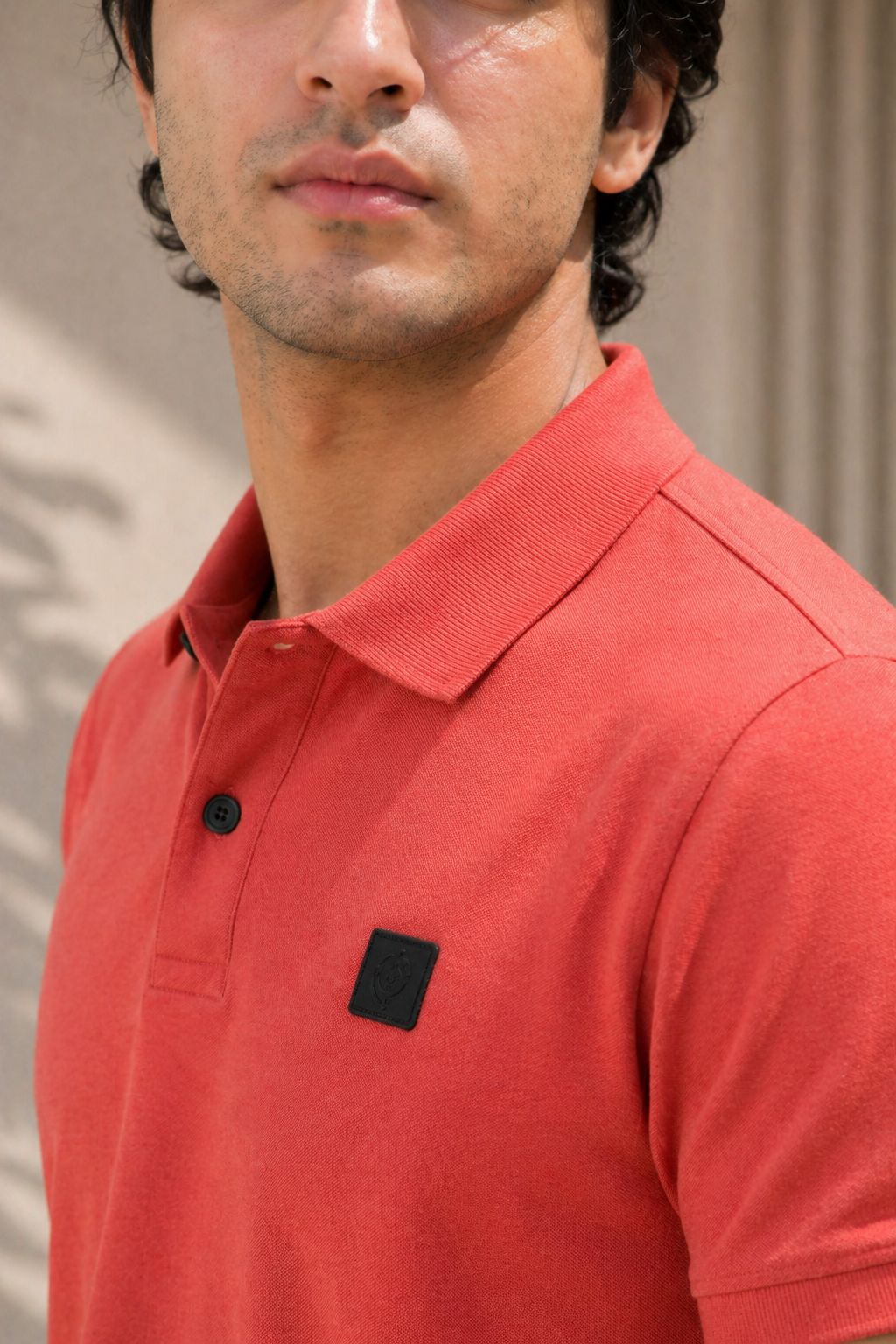 Man wearing a red polo shirt with a brand logo on a neutral background