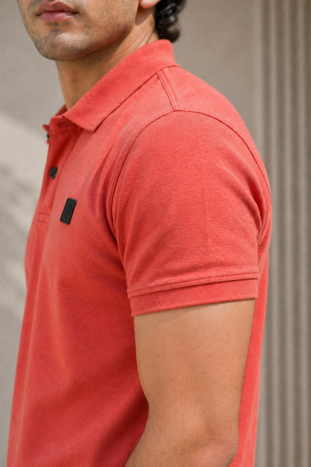 Man wearing a red polo shirt with a brand logo on a neutral background
