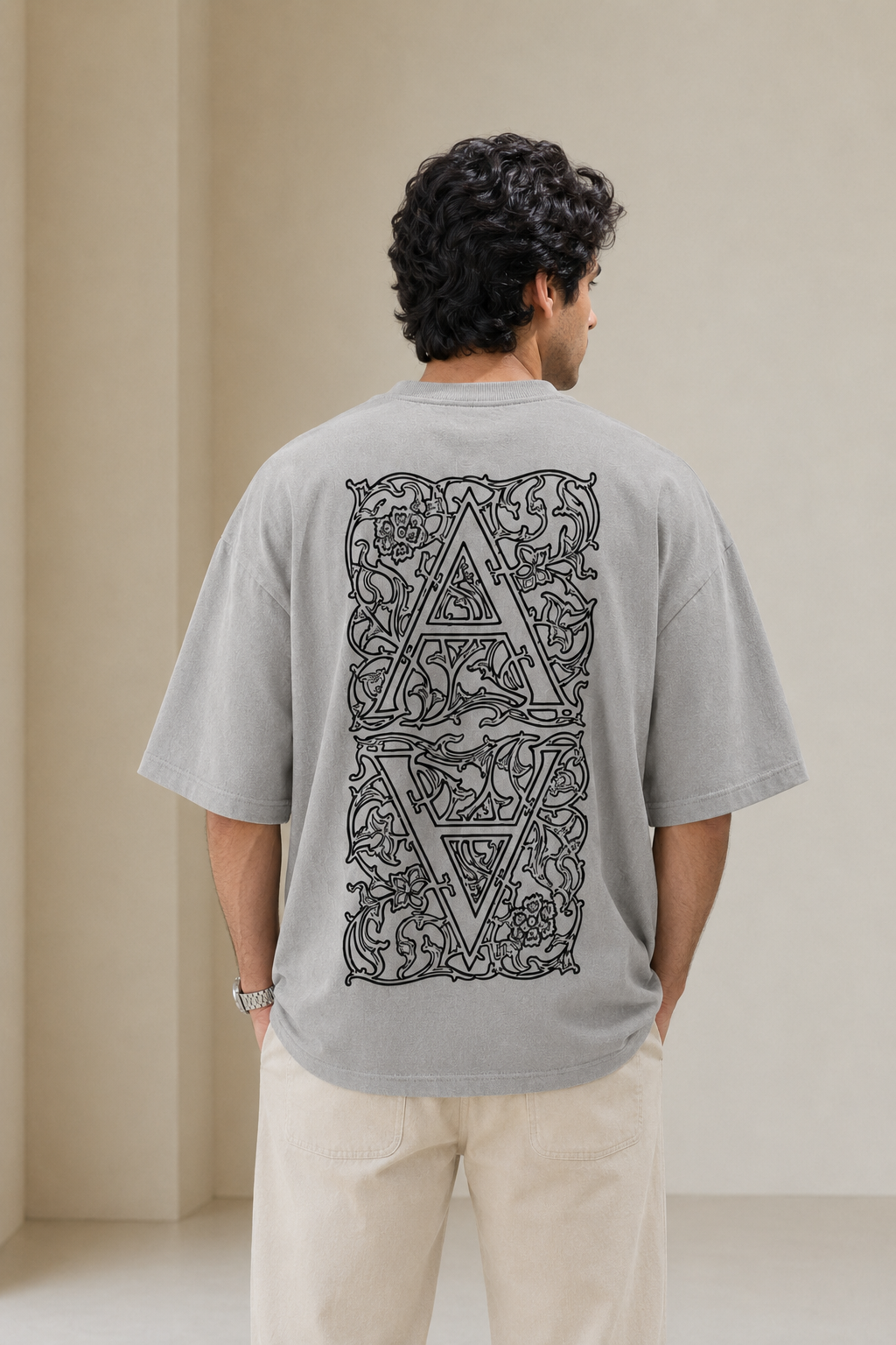 Man wearing a gray t-shirt with a decorative back design against a plain background