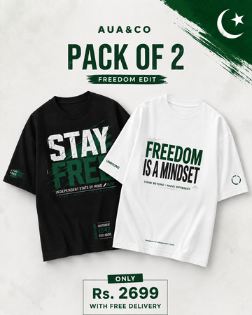 A promotional graphic for an AUA&CO 'Pack of 2' Freedom Edit featuring two graphic t-shirts: one black and one white. The black shirt displays 'STAY FREEDOM' in bold white and green text, while the white shirt displays 'FREEDOM IS A MINDSET' in green and black.