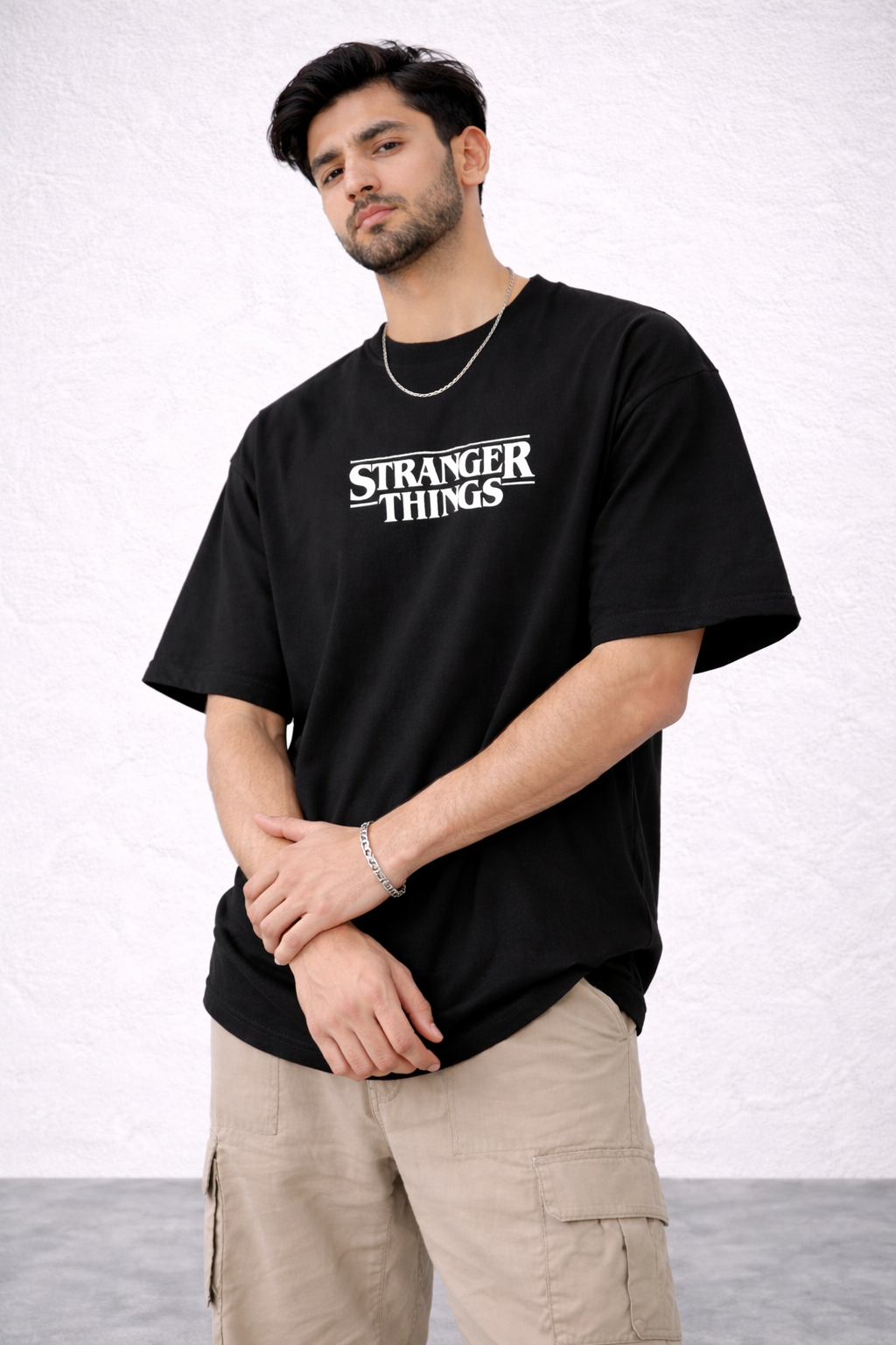 Person wearing a black 'Stranger Things' t-shirt against a white background | AUA&CO.