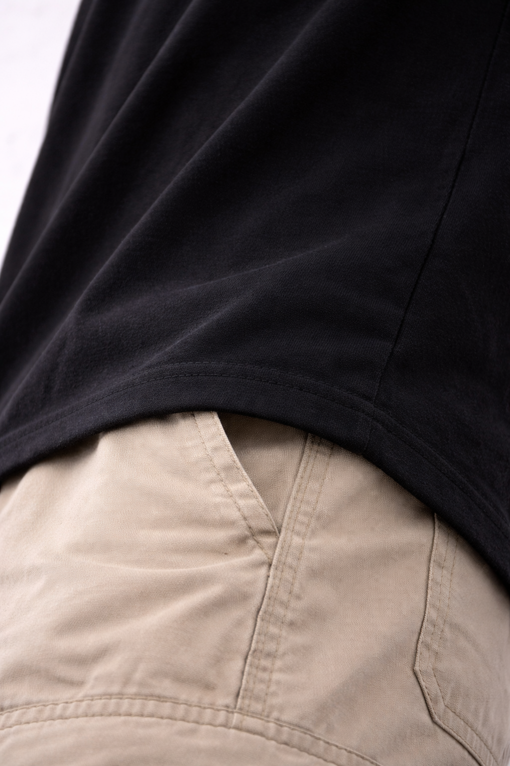 Close-up of a person wearing a black shirt and beige pants | by AUA&CO.