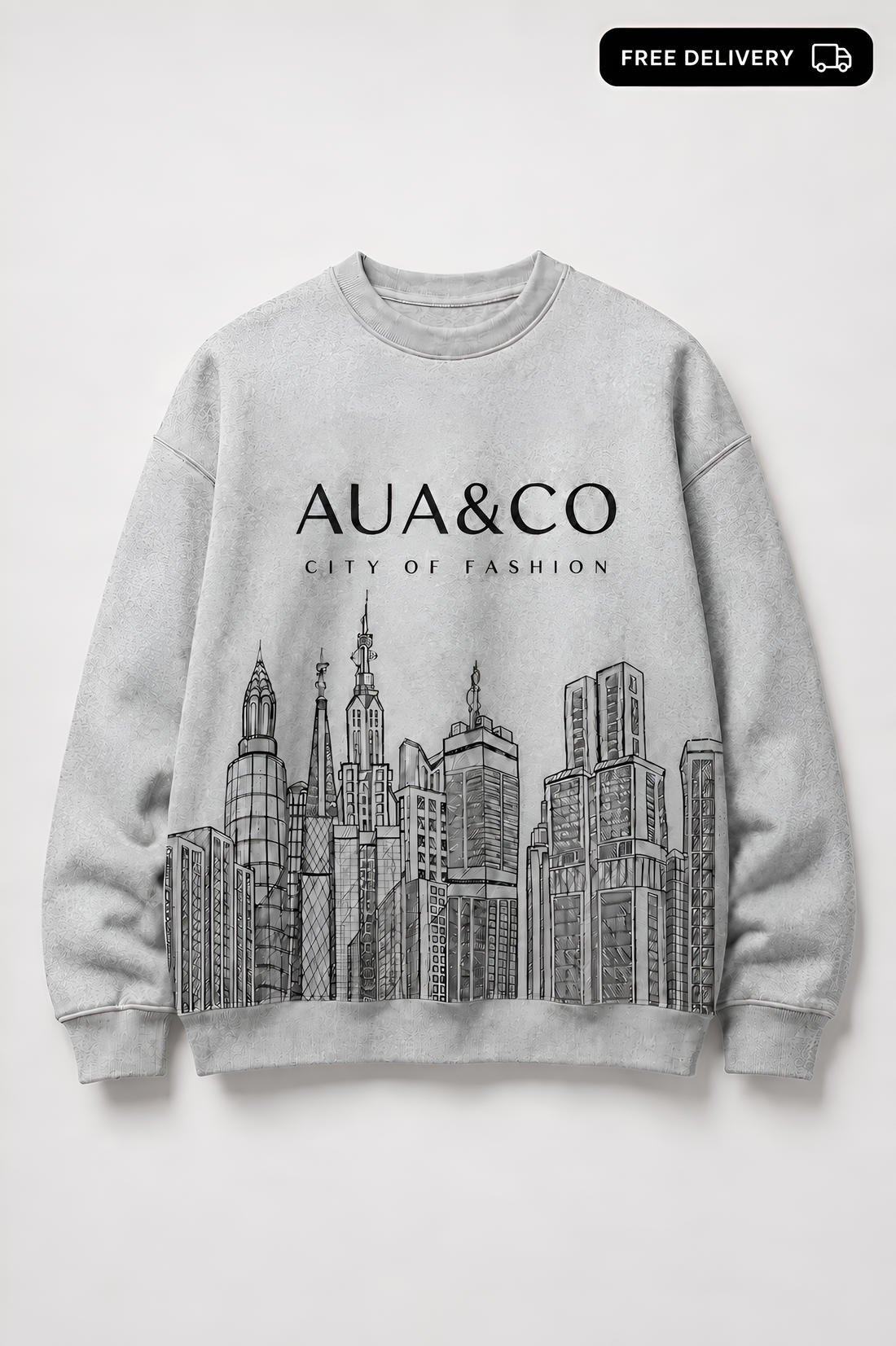 A light gray crewneck sweatshirt featuring a black line art graphic of skyscrapers and the text 'AUA&CO CITY OF FASHION' printed on the front, displayed against a neutral light gray background.