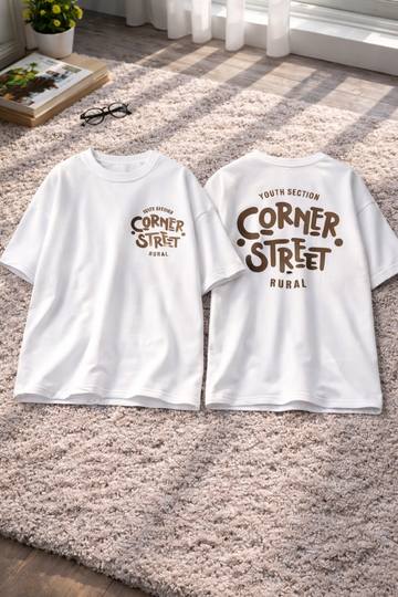 Two white t-shirts with 'Corner Street Rural' print on a carpeted floor.