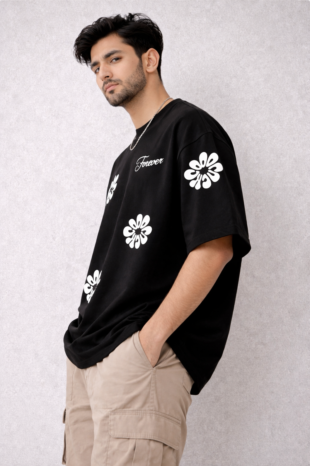 Man wearing a black t-shirt with white floral designs and text on a light gray background