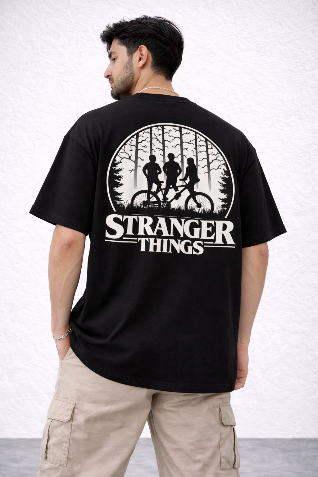 Person wearing a black 'Stranger Things' t-shirt with a graphic design on the back  | AUA&CO.