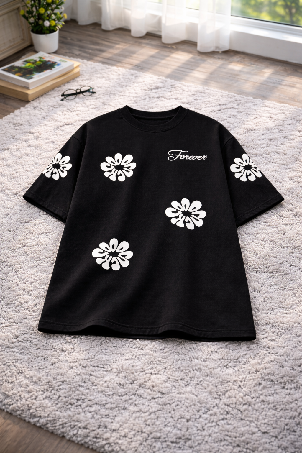 Black t-shirt with white floral designs on a gray carpet