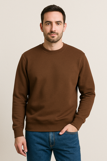 Man wearing a brown sweatshirt and blue jeans against a beige background