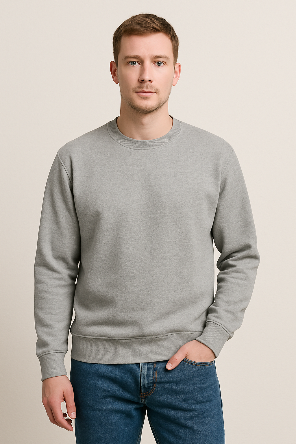 Man wearing a gray sweatshirt and blue jeans against a beige background