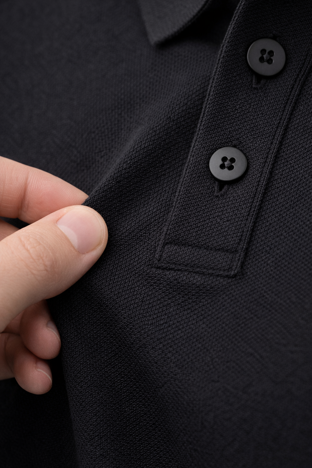 Close-up of a black jacket with buttons and a hand adjusting the collar.
