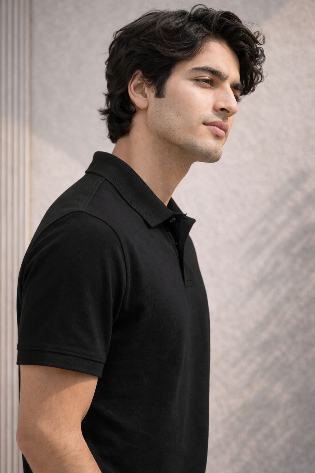 Man wearing a black polo shirt against a neutral background