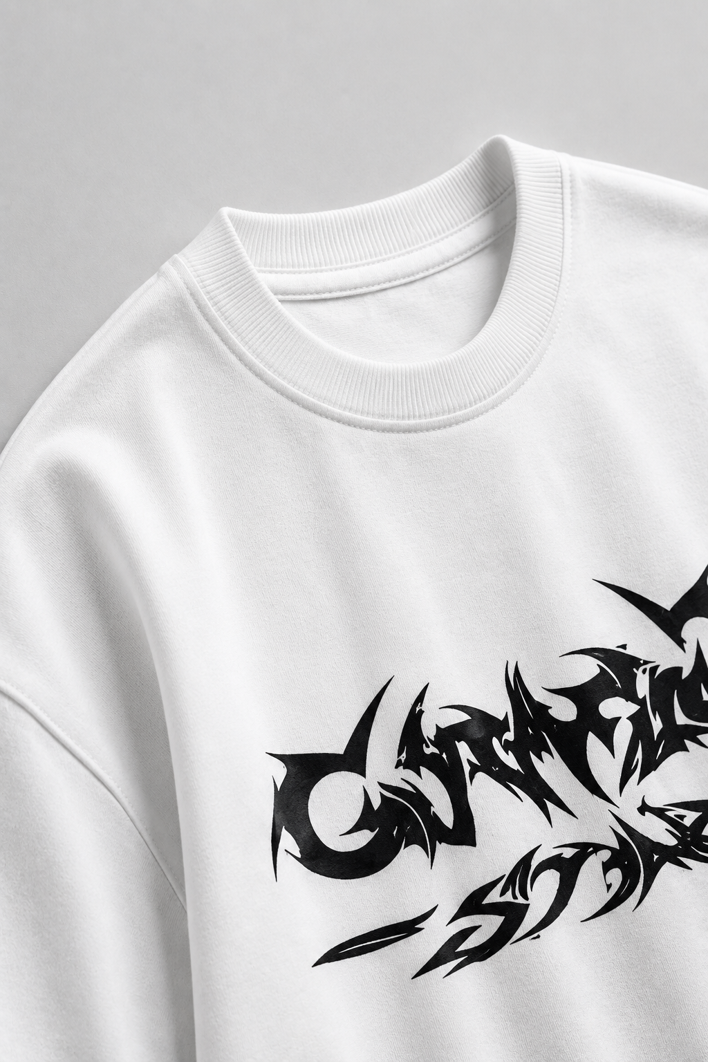 White sweatshirt with black tribal-style text design on a gray background