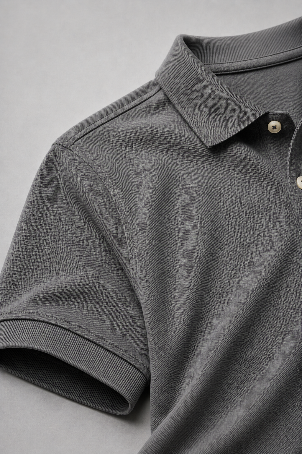 Close-up of a gray polo shirt with collar and buttons on a light gray background