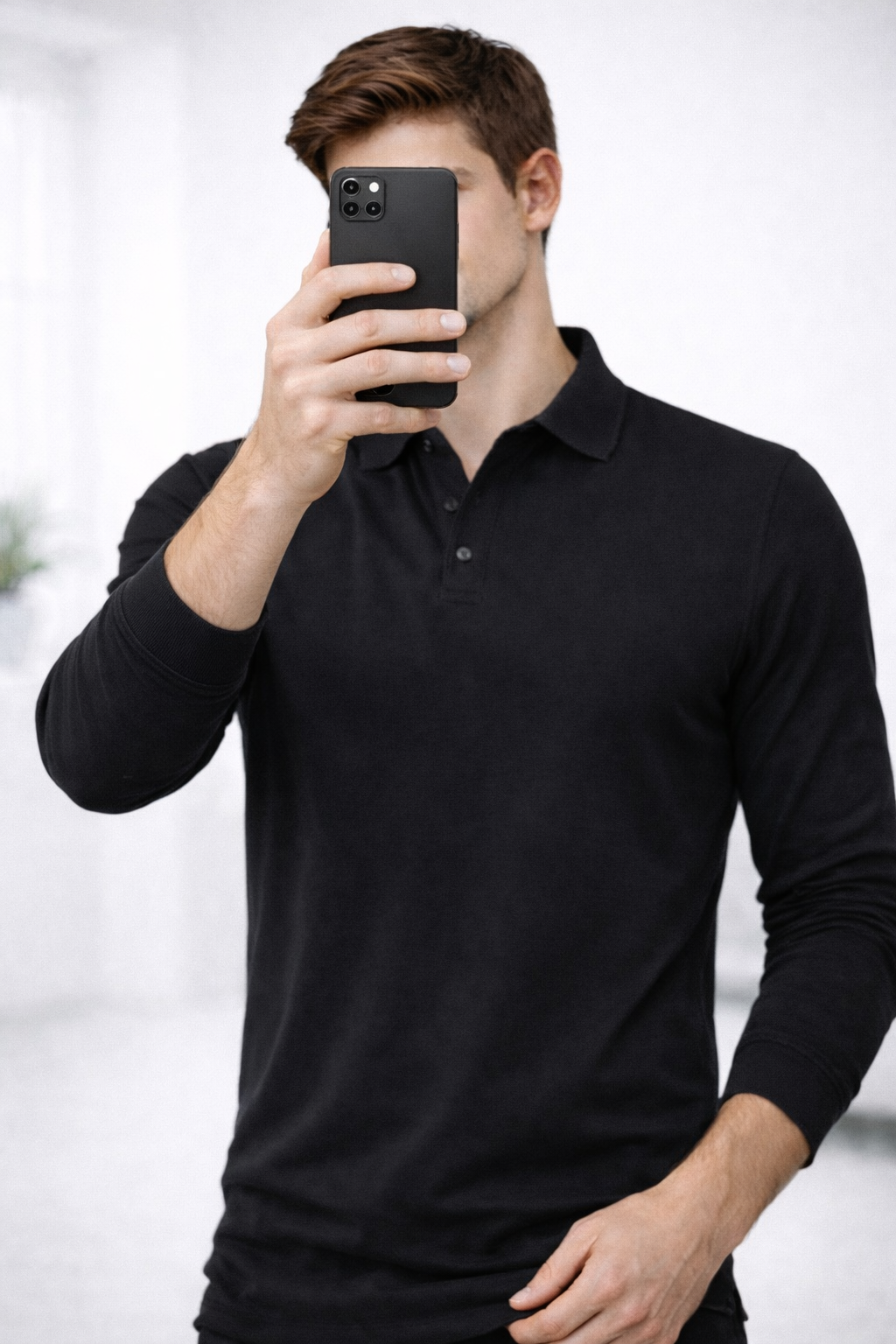 Man wearing a black long-sleeve polo shirt against a light background