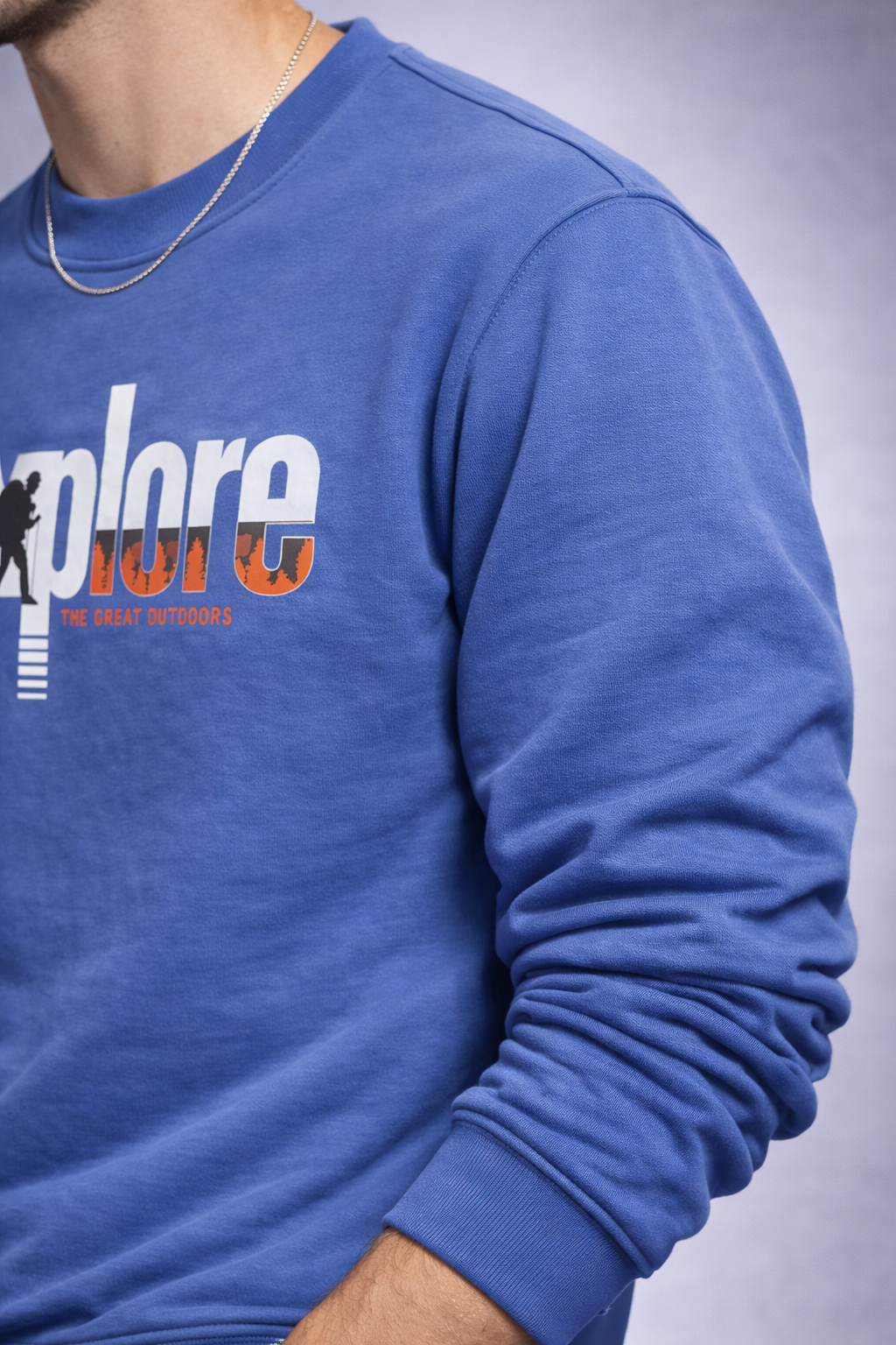 Blue sweatshirt with 'explore' printed on it against a neutral background