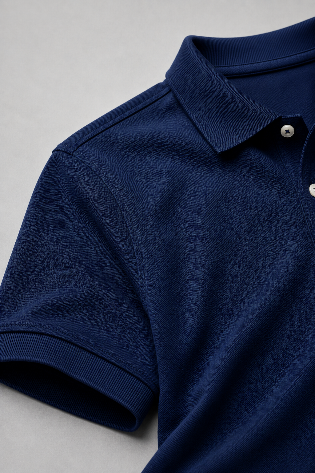 Close-up of a navy blue polo shirt on a light gray background
