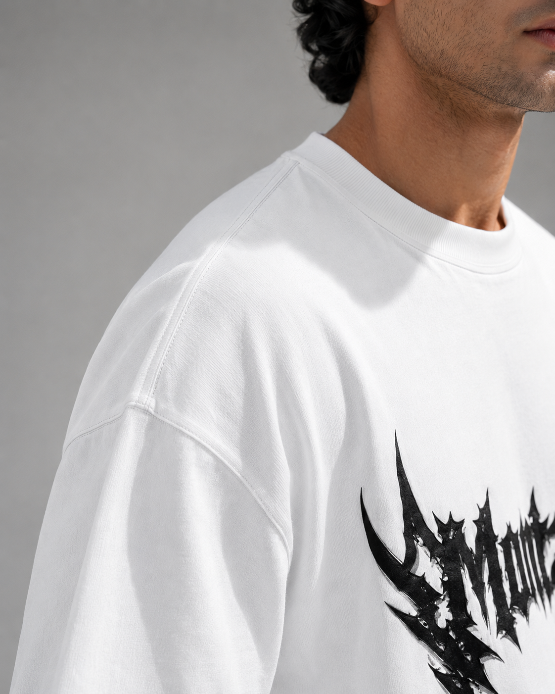 White sweatshirt with black graphic design worn by a person on a gray background