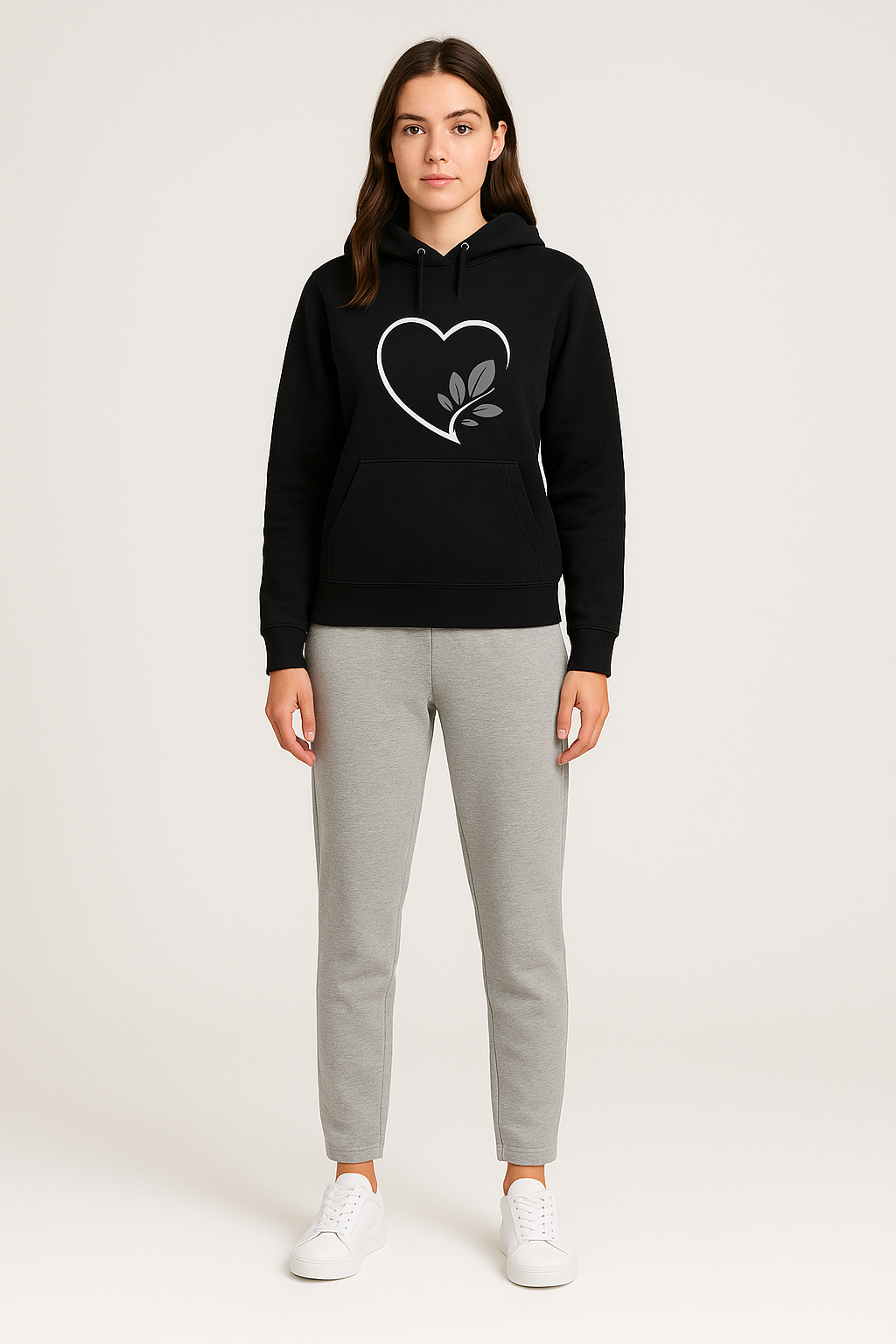 Person wearing a black hoodie with a heart design and gray pants on a white background