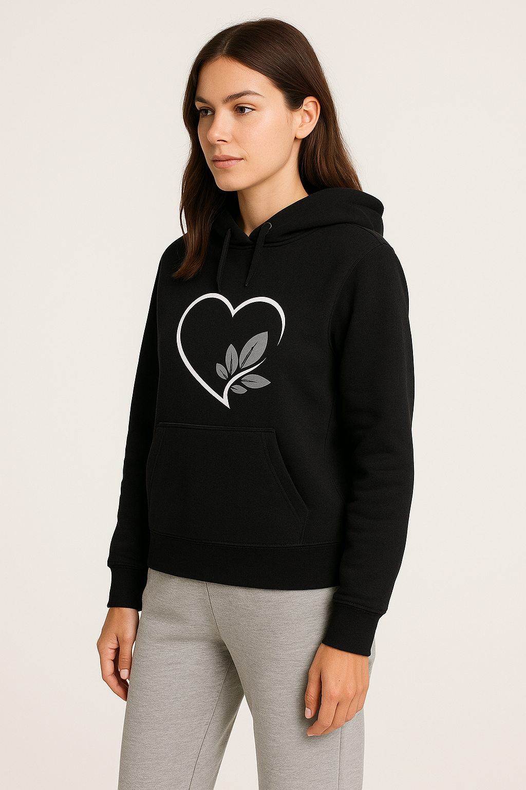 Person wearing a black hoodie with a heart design and gray pants on a white background